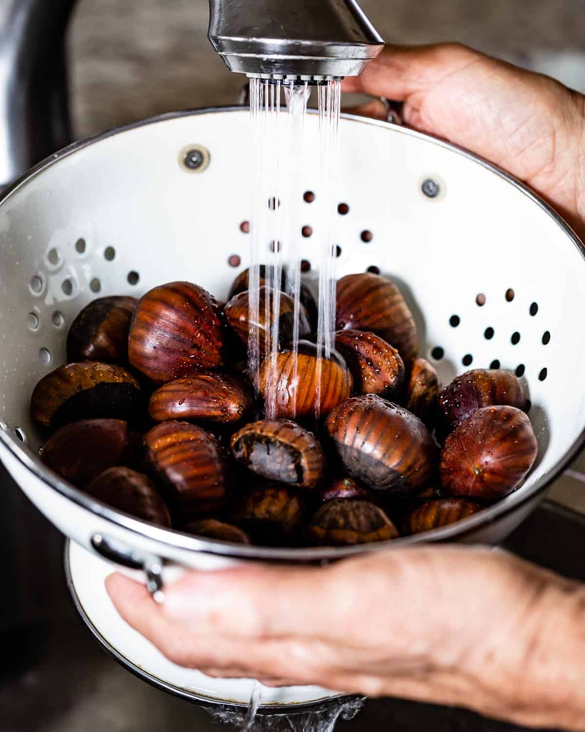 person rinsing chestnuts in a colander