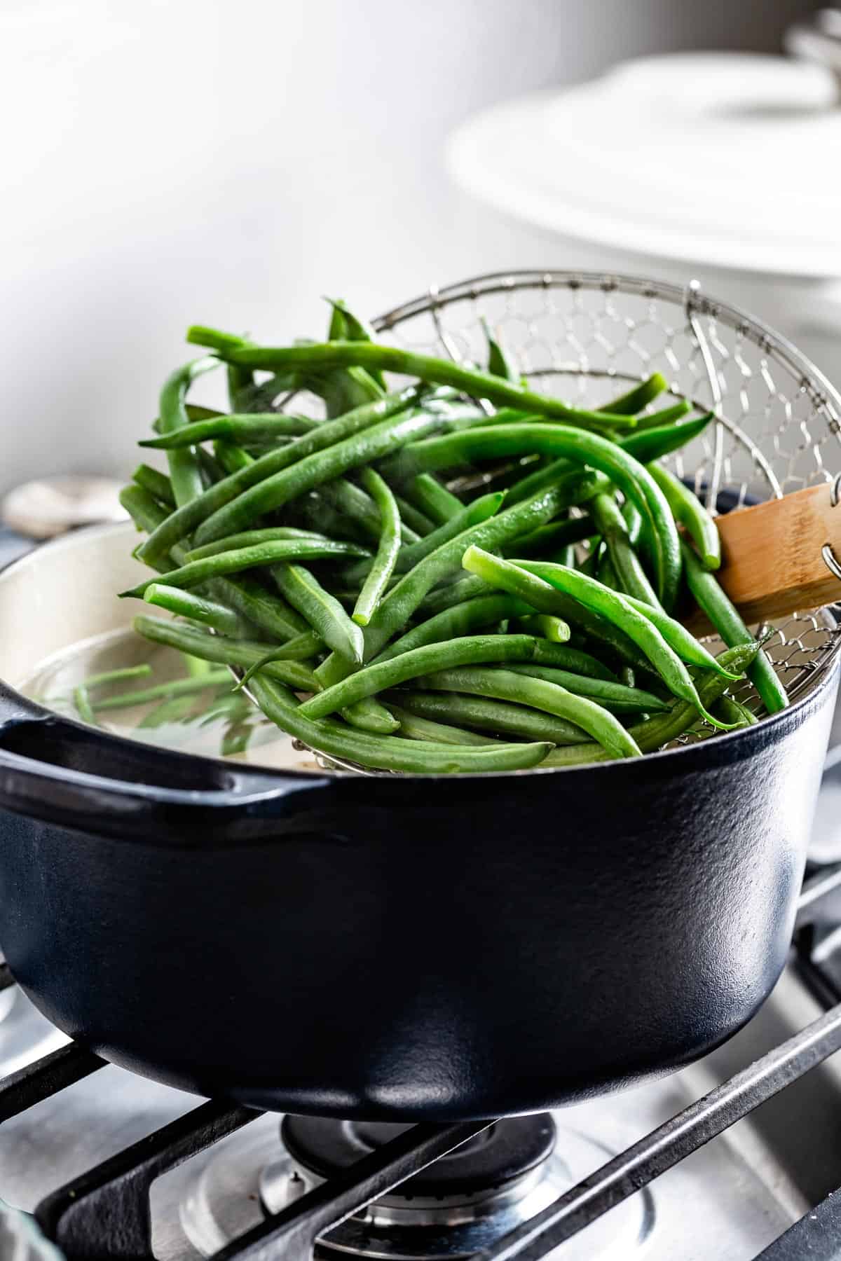 person placing green beans in boiling water