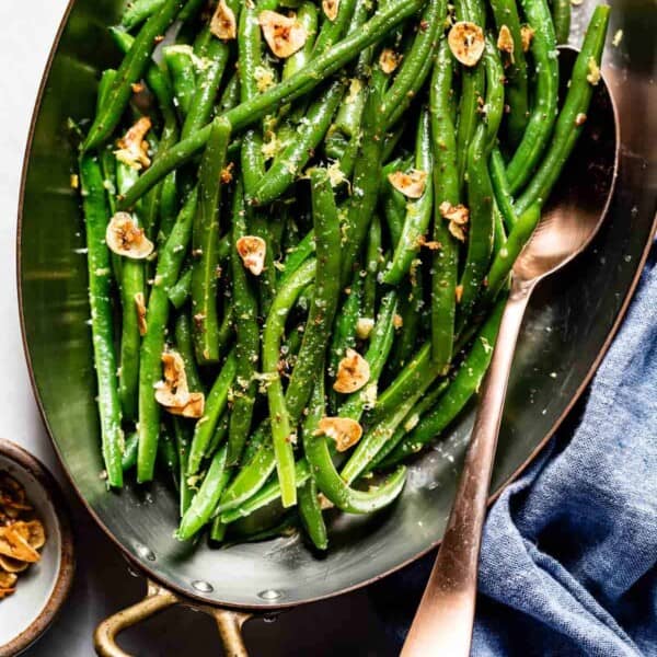 Buttery Garlic Green Beans in a pan with a spoon on the side