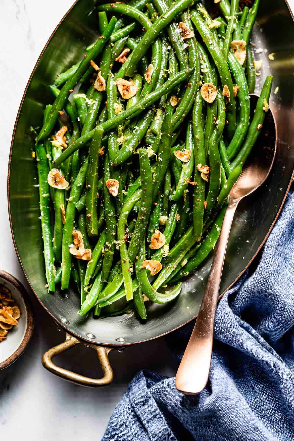 A green beans vegetable side dish in a skillet with a spoon on the side