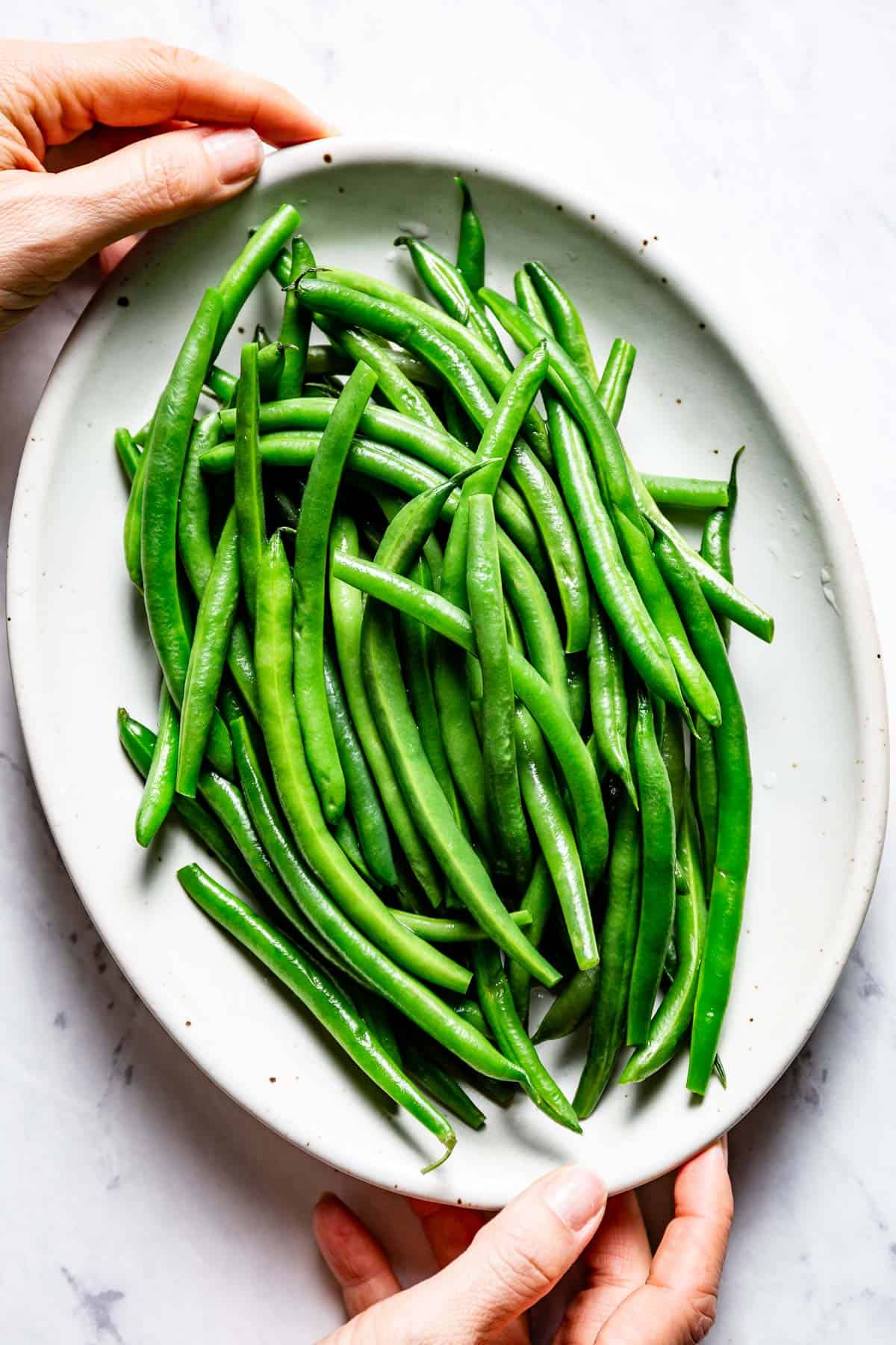 boiled green beans on a plate being served from the top