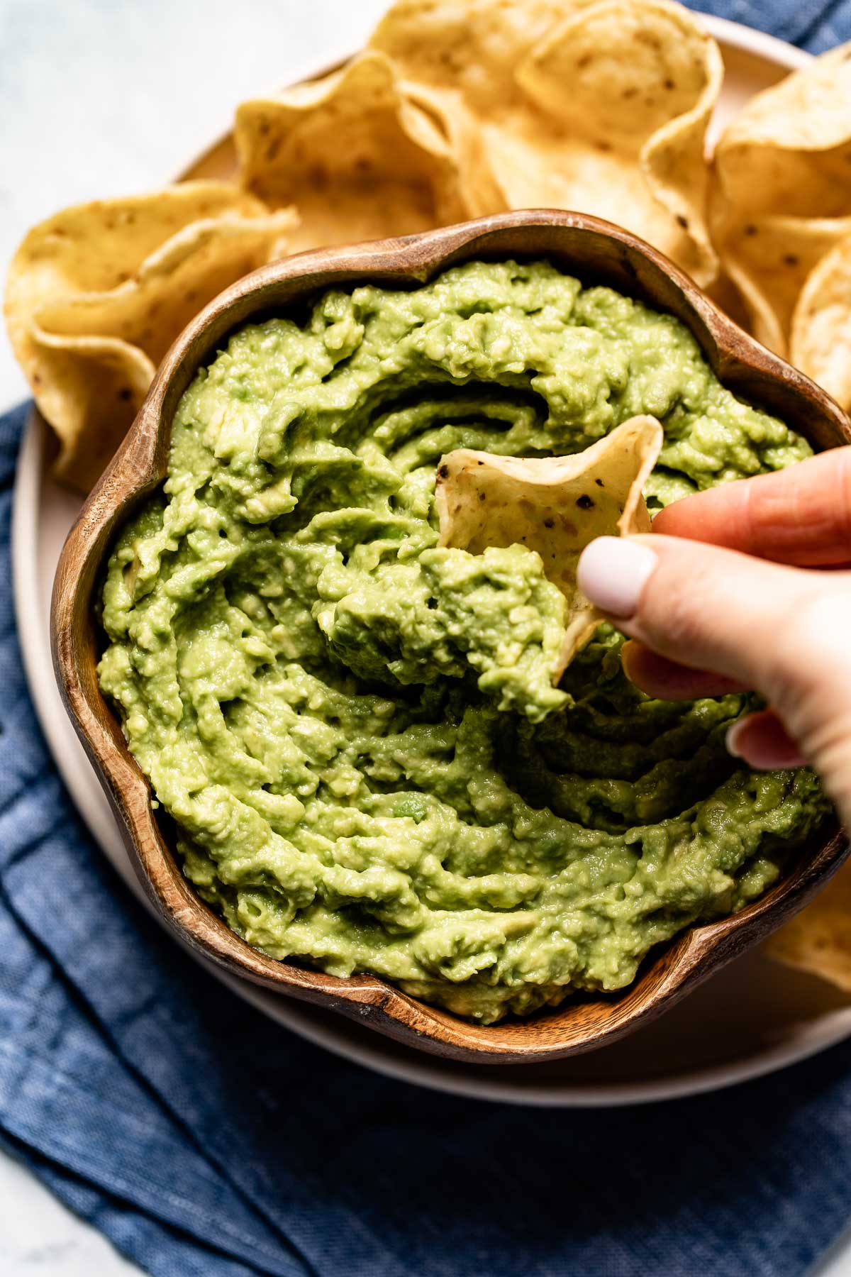 Person scooping guac with a chip from the top view