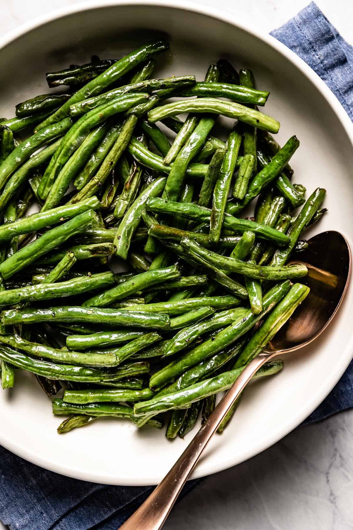 Air fryer green beans in a bowl with a spoon on the side