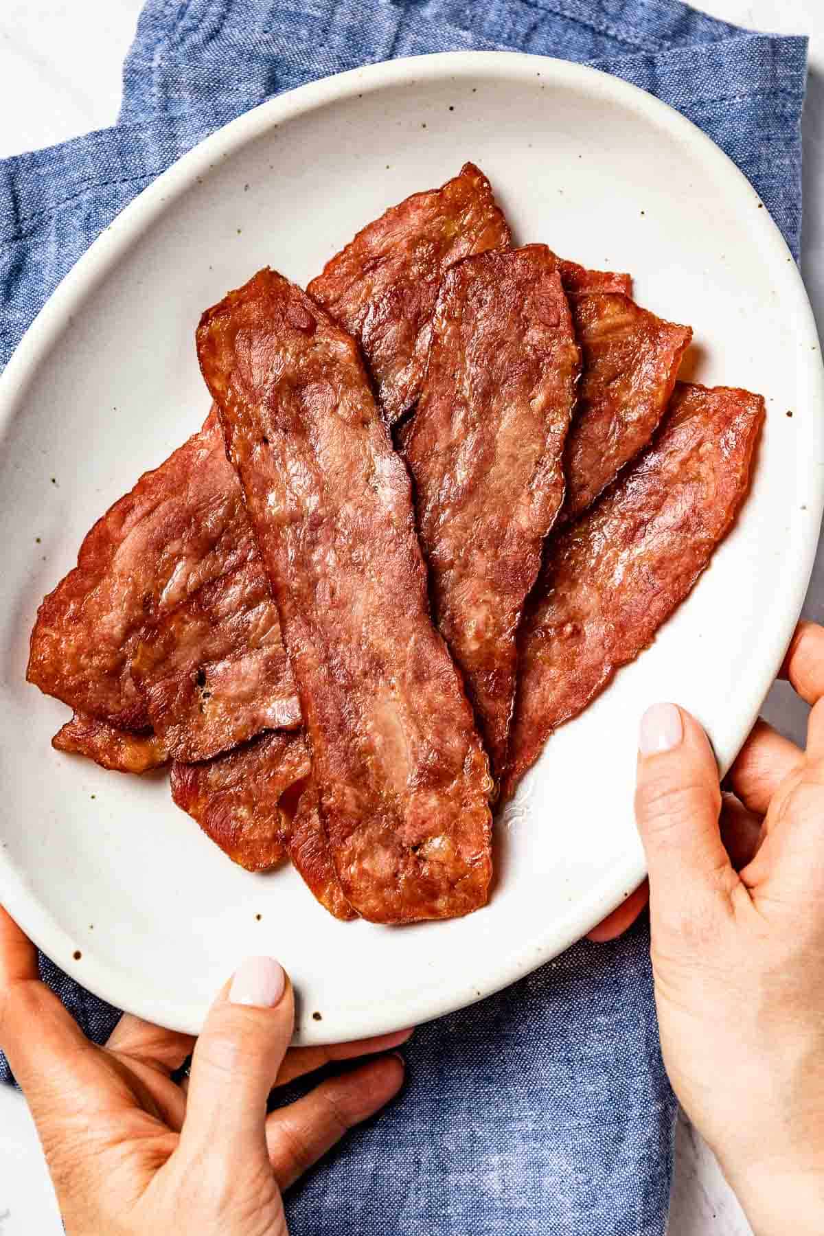 Person serving crispy turkey bacon in a plate