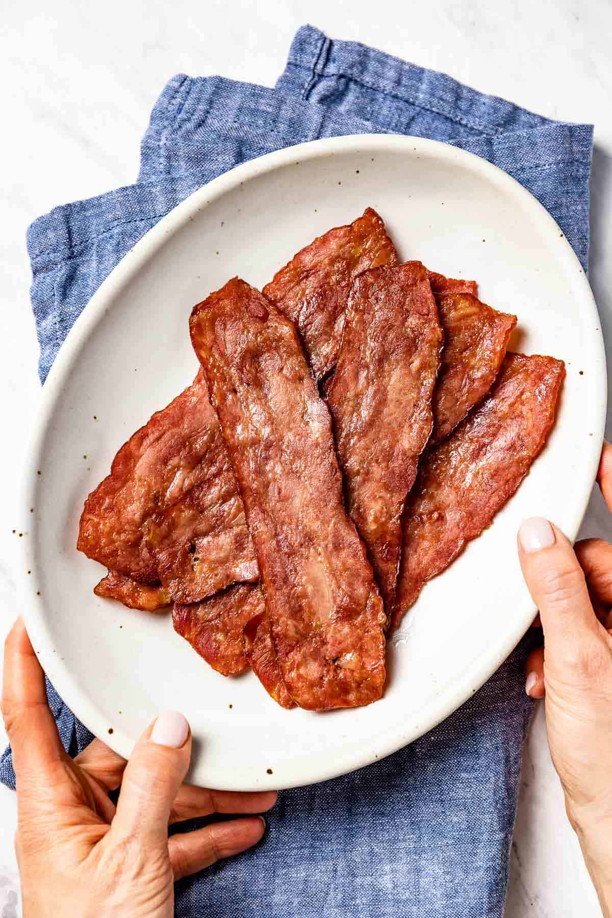 Cooked turkey bacon in a plate served by a person