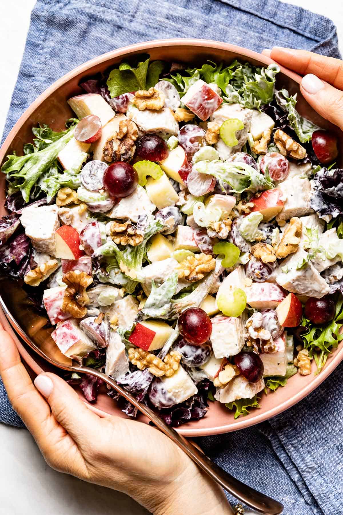 person serving chicken waldorf salad in a bowl