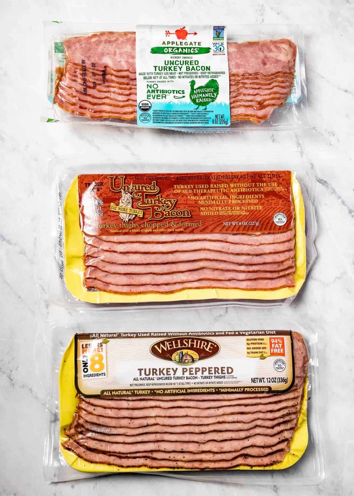 three different supermarket turkey bacon placed on the kitchen counter