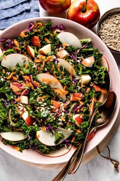 Kale Apple Slaw in a bowl with two tablespoons on the side