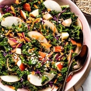 Kale Apple Carrot Slaw in a bowl with two spoons on the side
