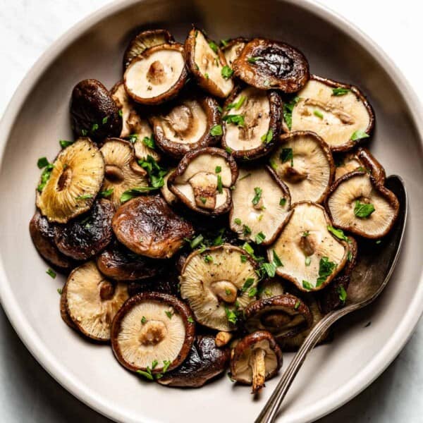 roasted shiitake mushrooms in a plate with a spoon on the side