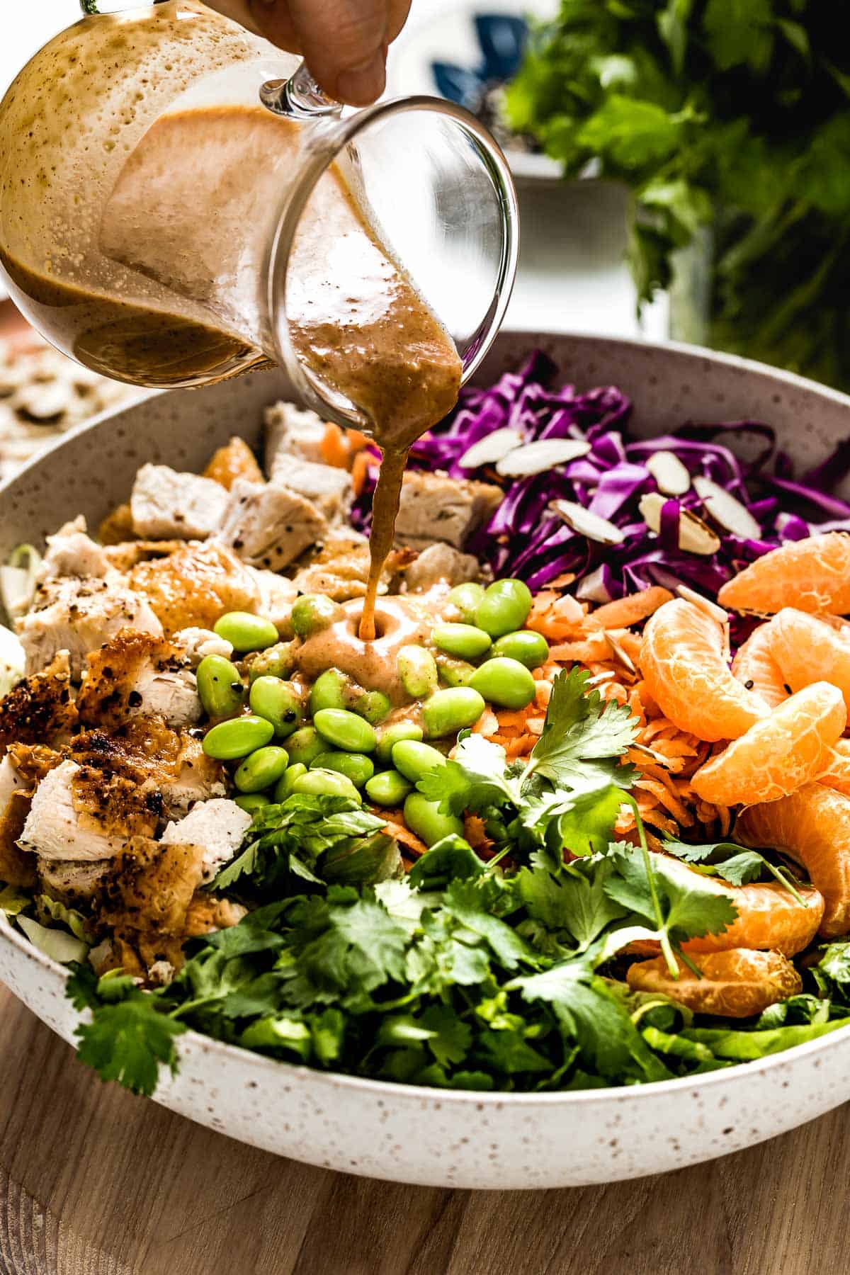 Asian Sesame Chicken Salad being drizzled with the dressing