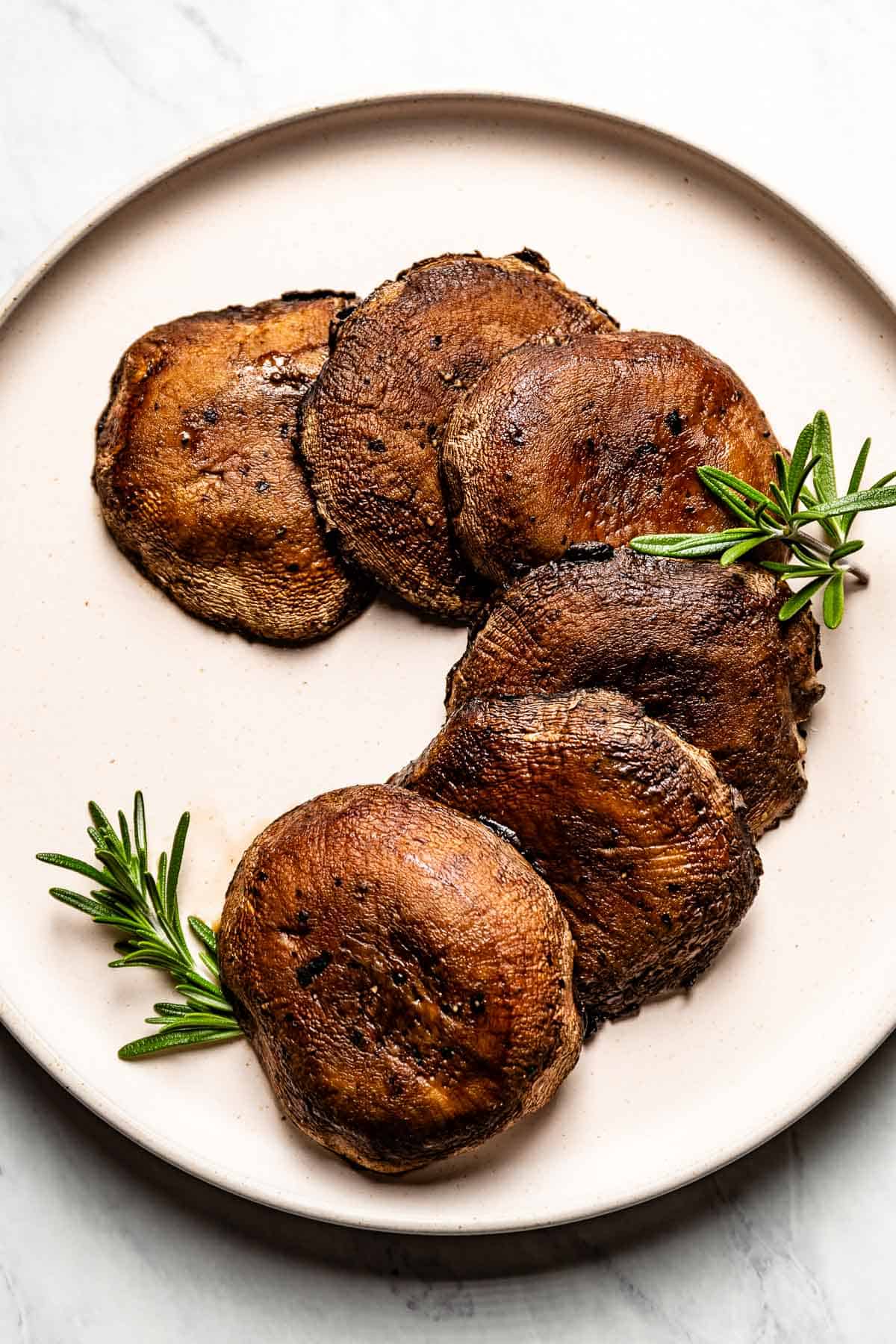 Roasted portobello mushrooms on a plate garnished with rosemary