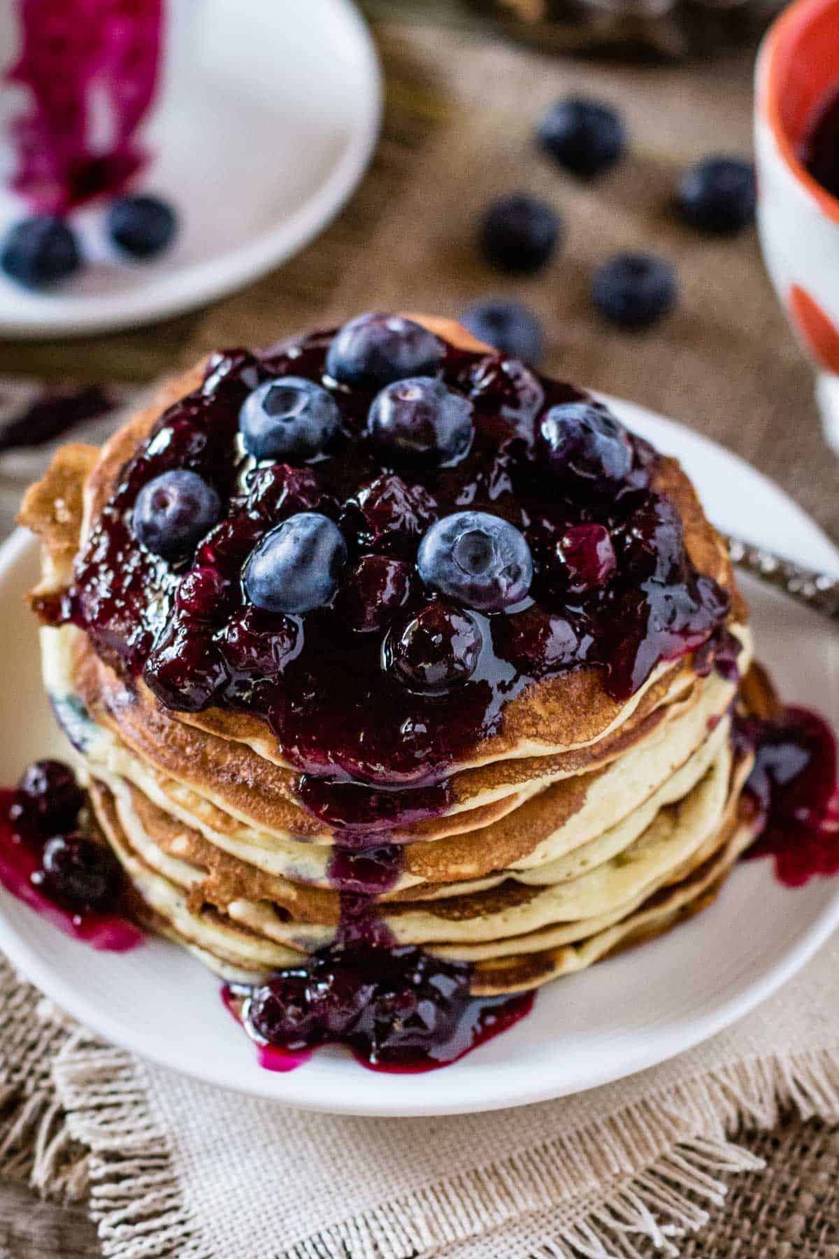 ricotta pancakes stacked onto each other and topped off with blueberry sauce