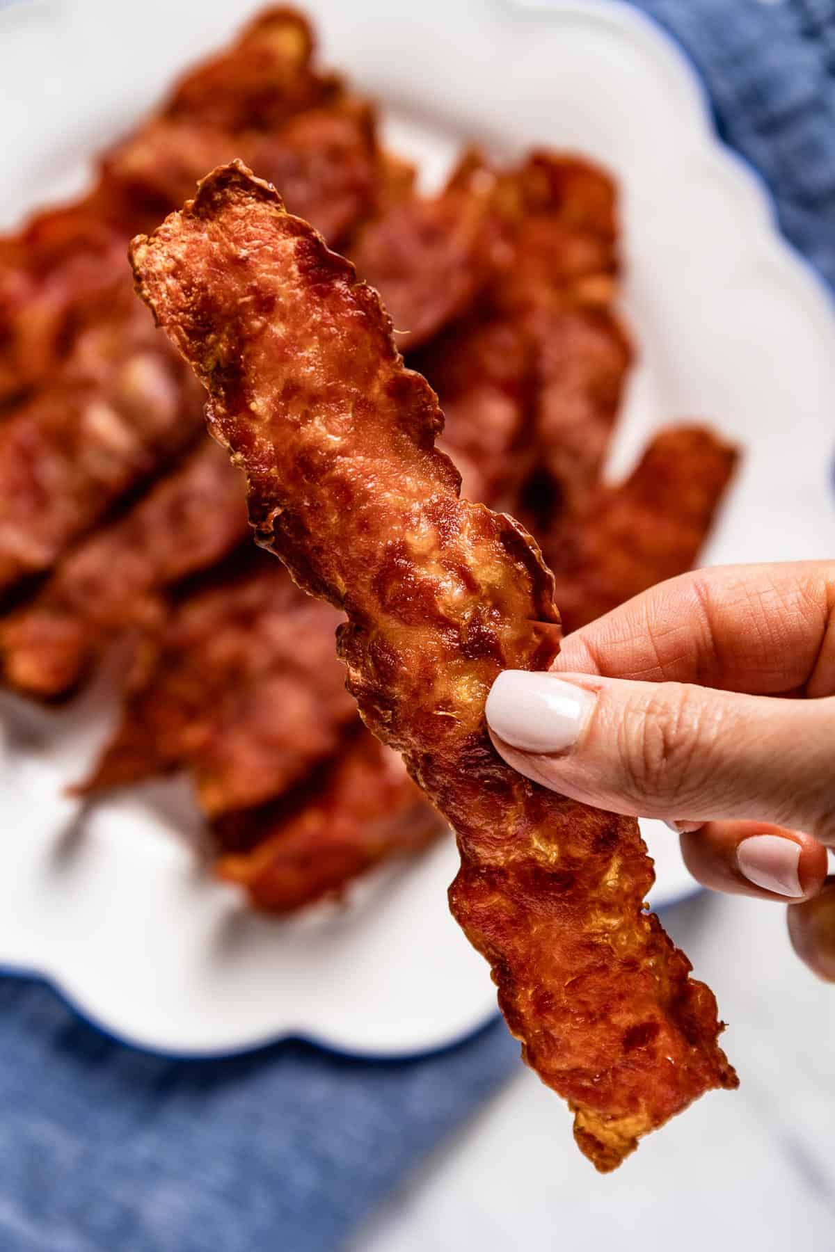 Crispy turkey bacon cooked in air fryer is held by a woman