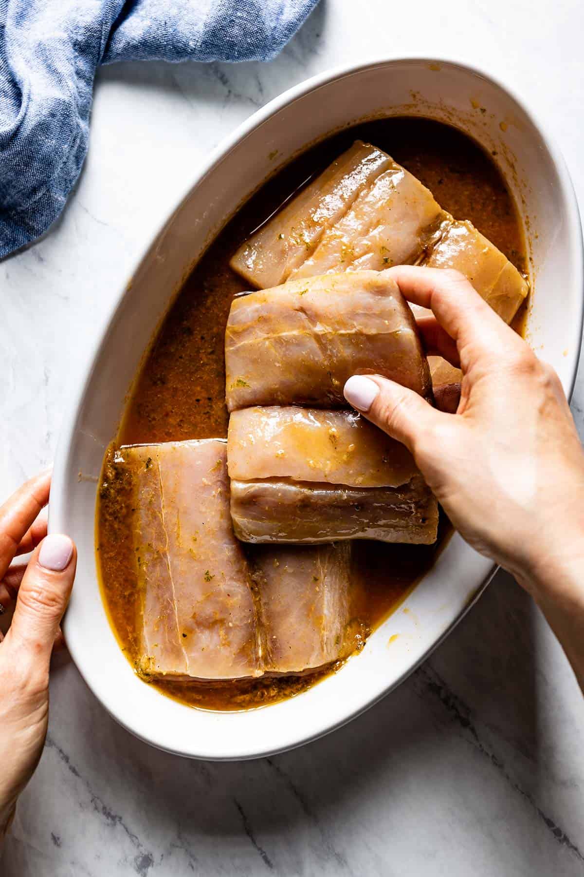 person placing mahi mahi in marinade