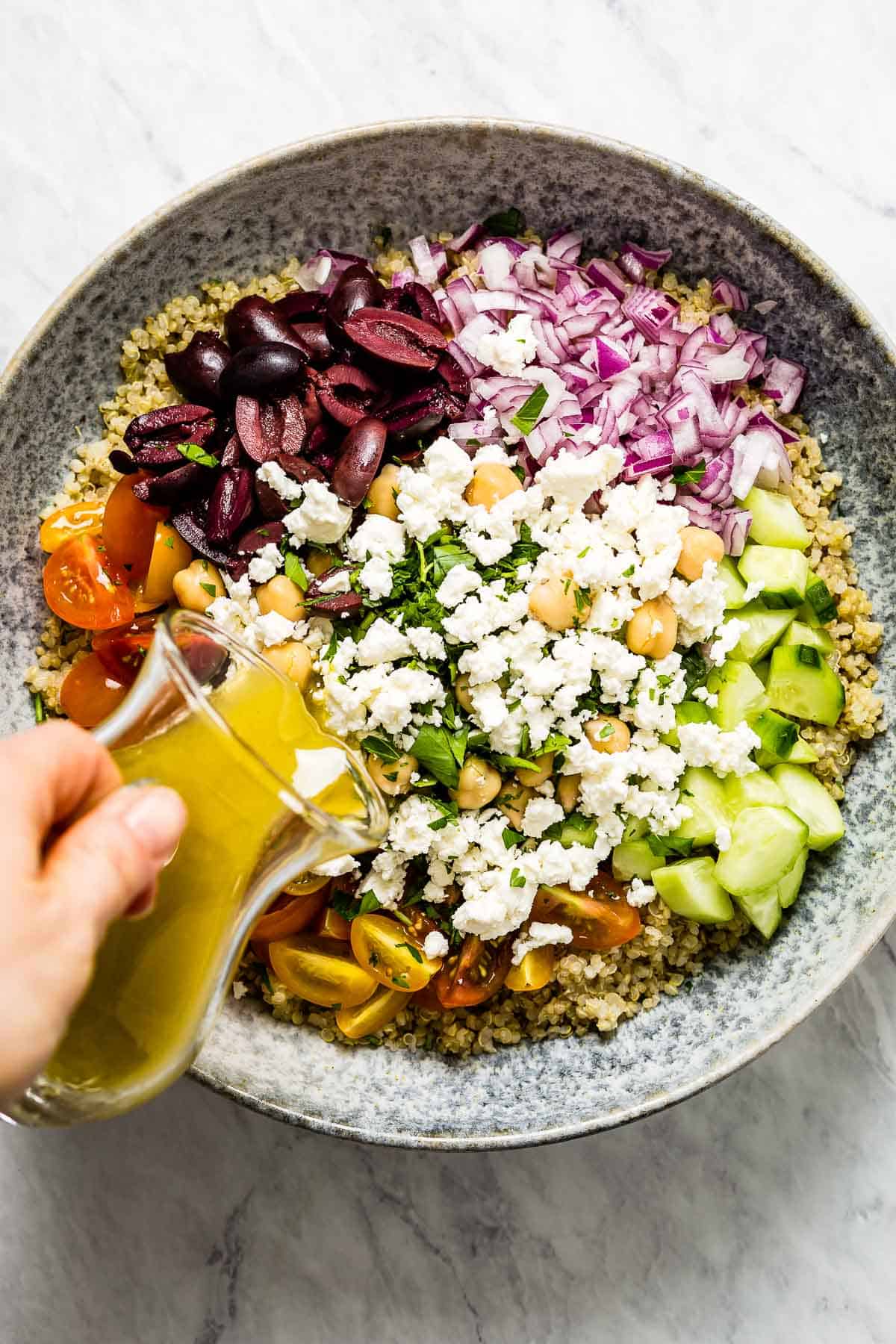 Quinoa salad being drizzled with the dressing