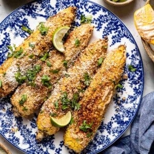 air fryer elotes on a plate with toppings from the top view