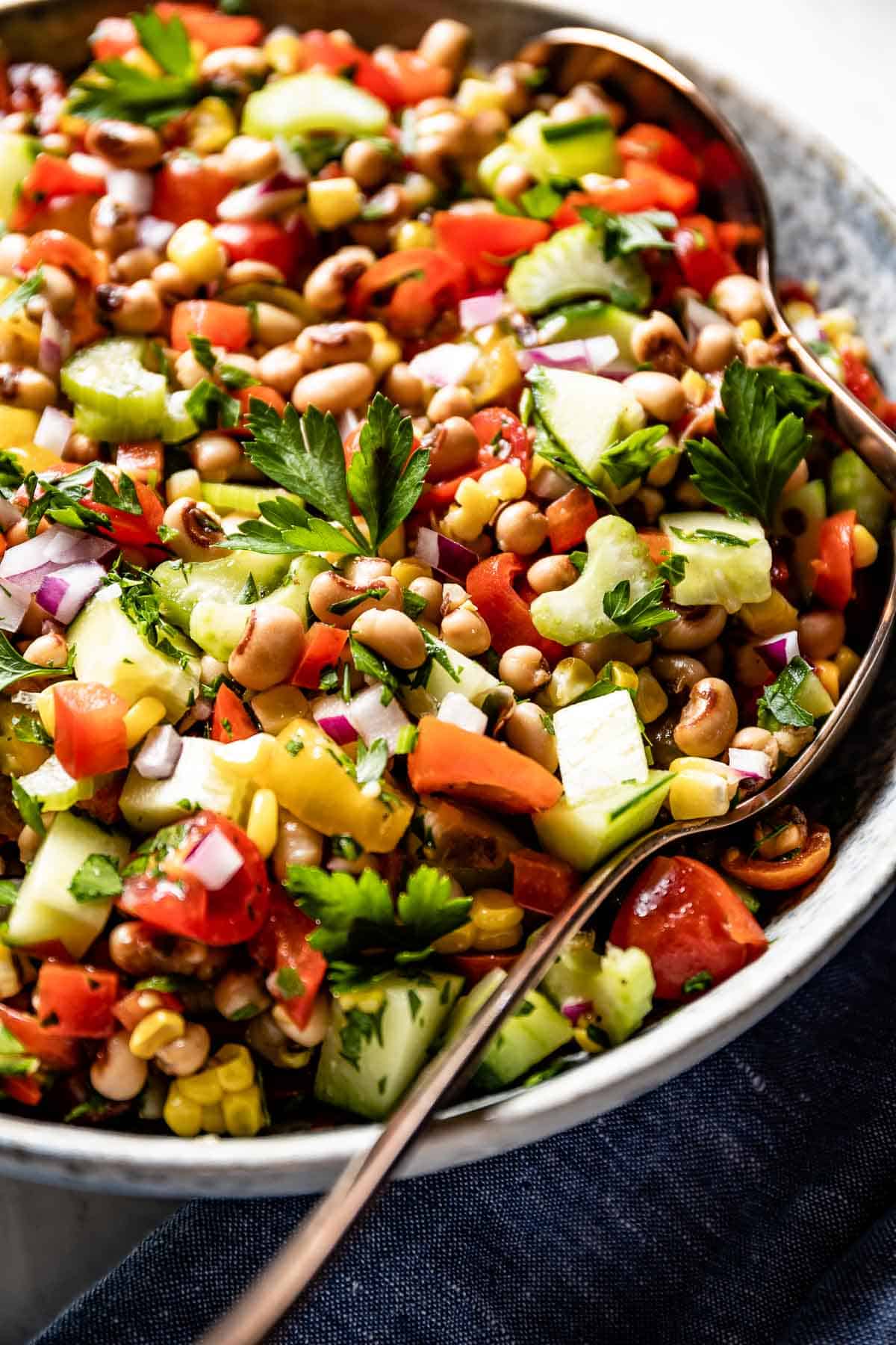 black eyed pea tomato salad garnished with parsley with spoons on the side