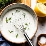 Yogurt dill sauce in a bowl with a whisk in the bowl from the top view