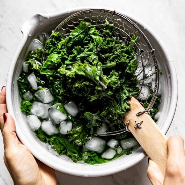 A person showing how to blanch kale in water from the top view.