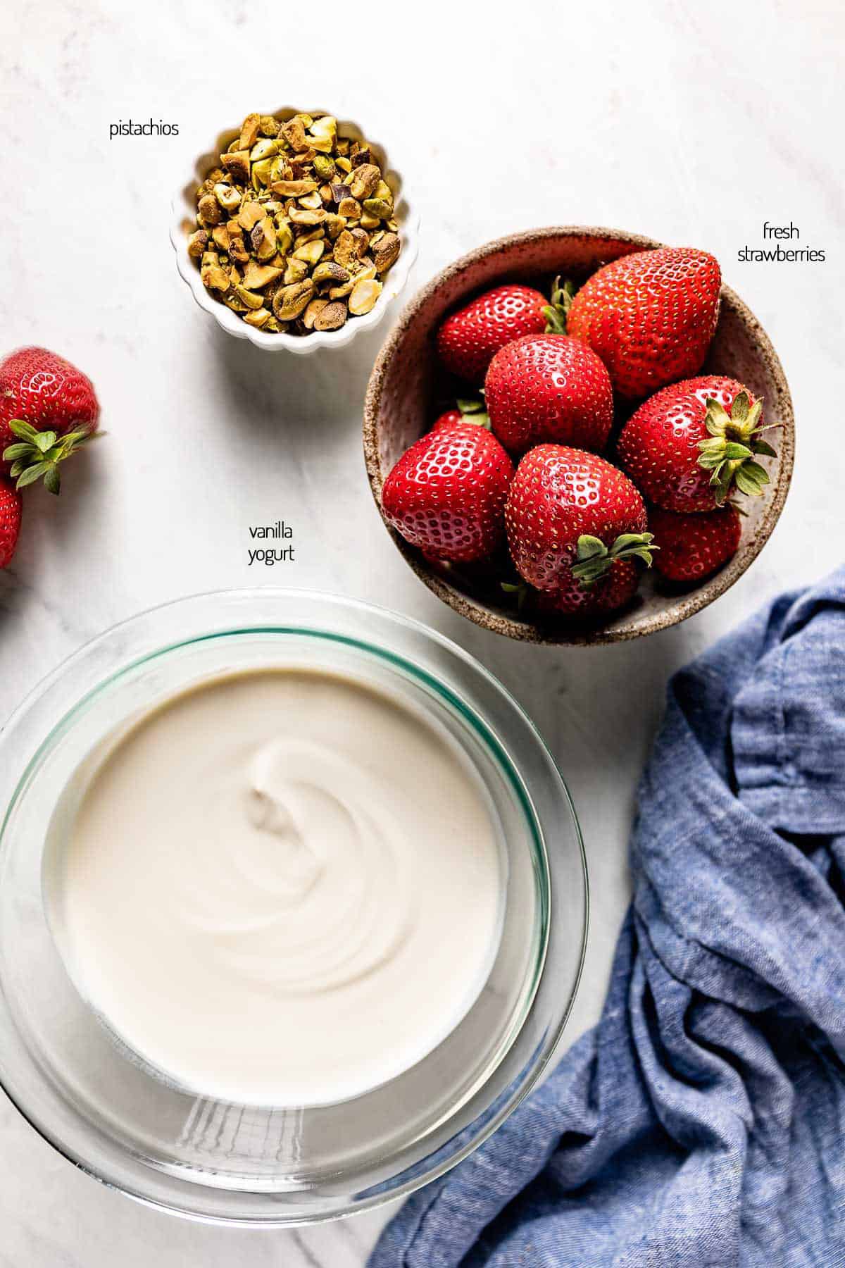 yogurt, strawberries, and pistachios in bowls as ingredients for fro yo bark