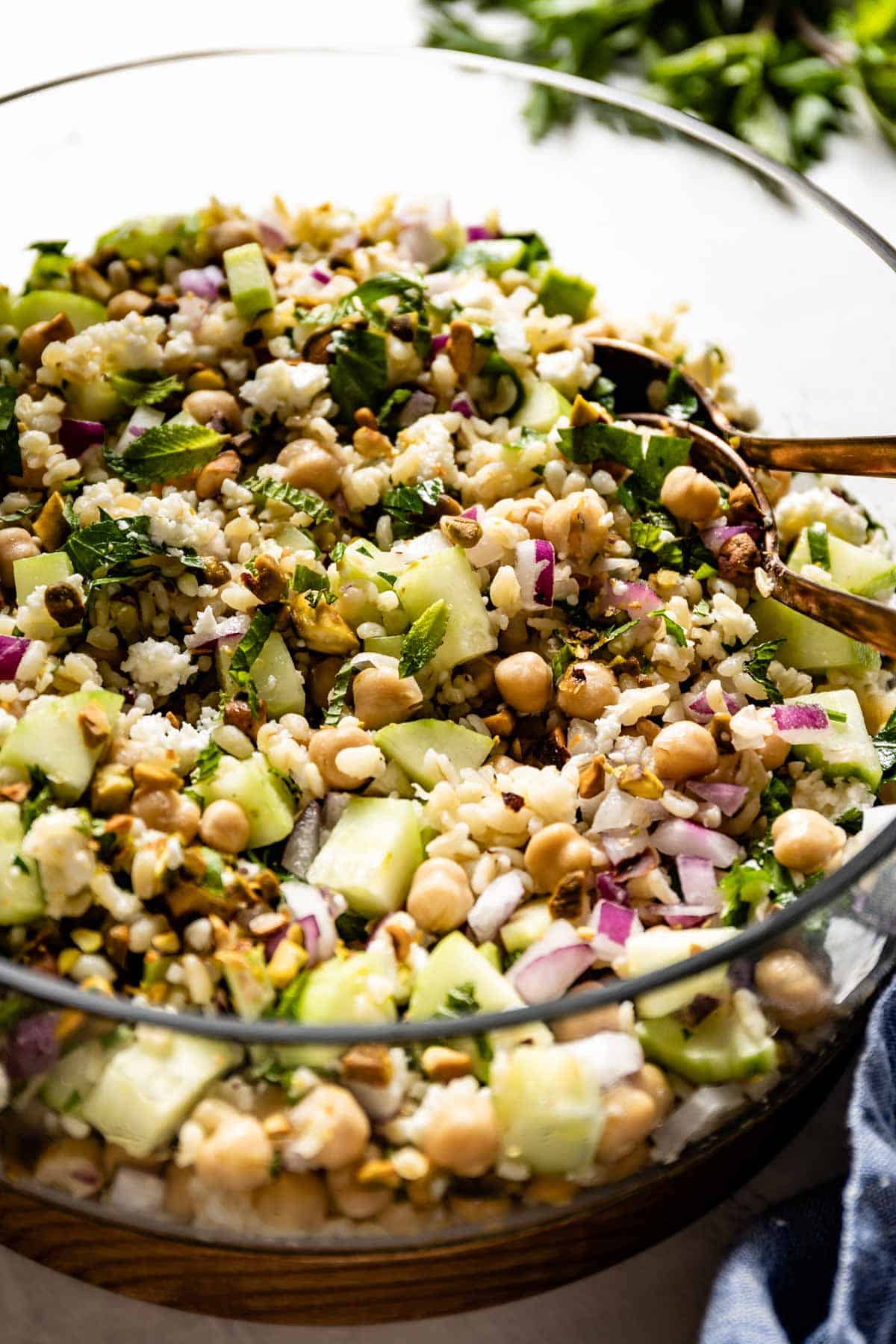 A salad with bulgur with spoons in the bowl from the side view. 