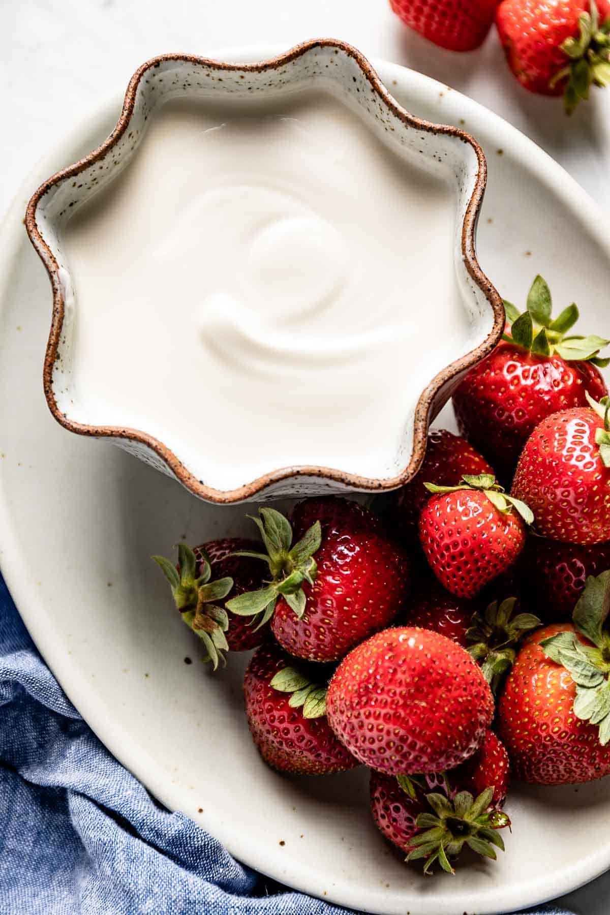 vanilla yogurt in a bowl with strawberries on the side from the top view