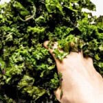 Person massaging kale by hand in a bowl.