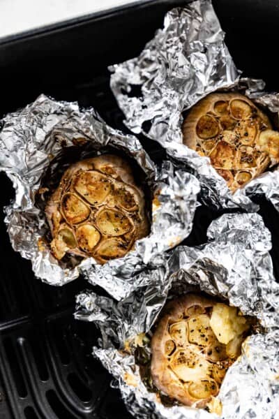 Heads of roasted garlic wrapped in foil in the air fryer.