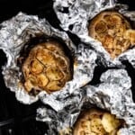 Air fryer roasted garlic cloves wrapped in foil from the top view.