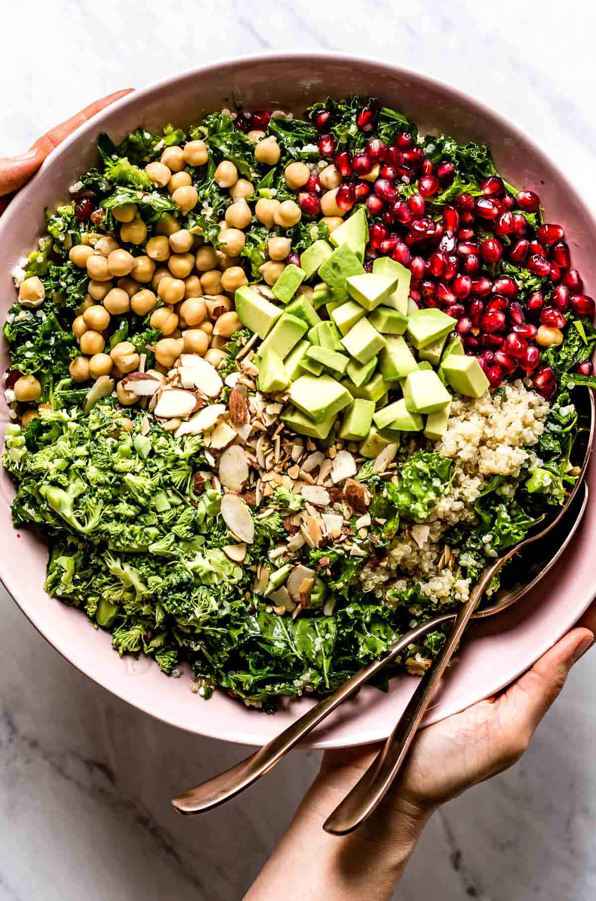 Quinoa and Kale salad served in a bowl by a person from the top view.