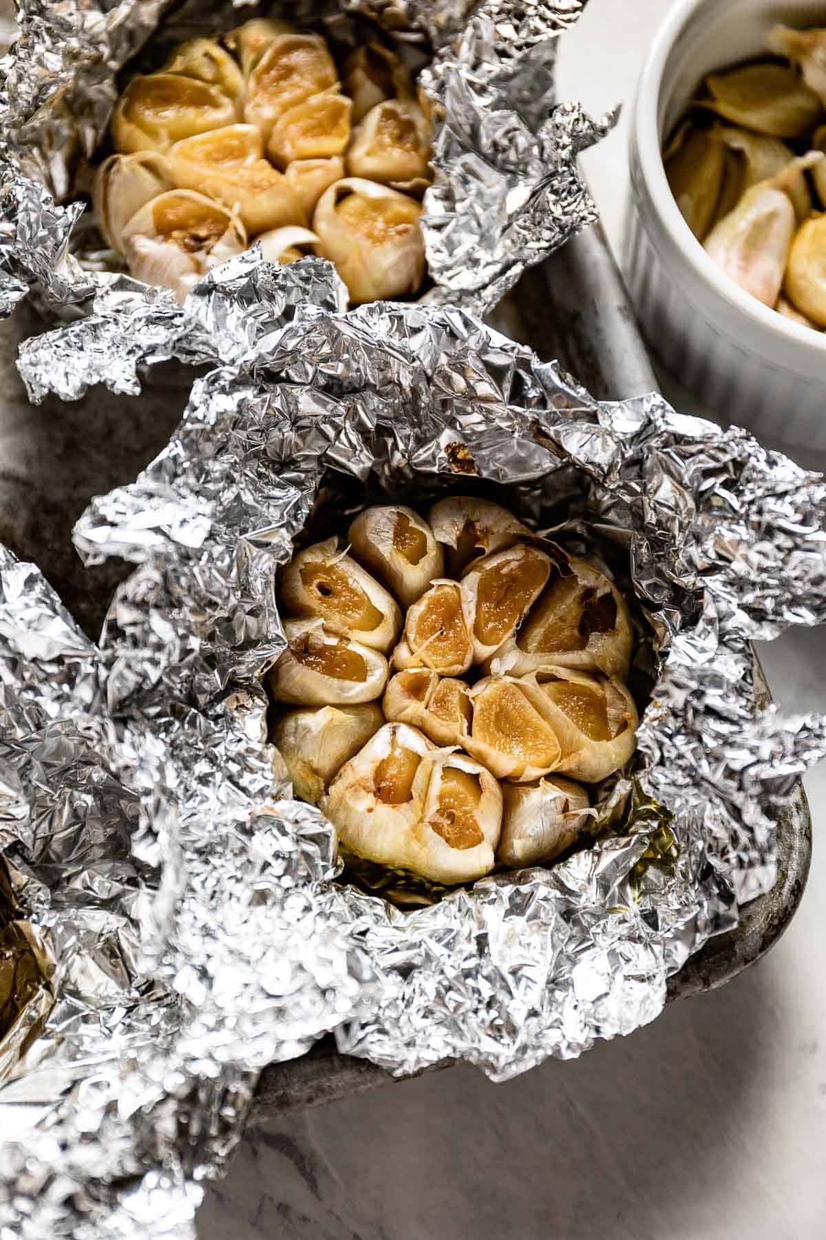 A top view of foil-wrapped heads of roasted garlic.
