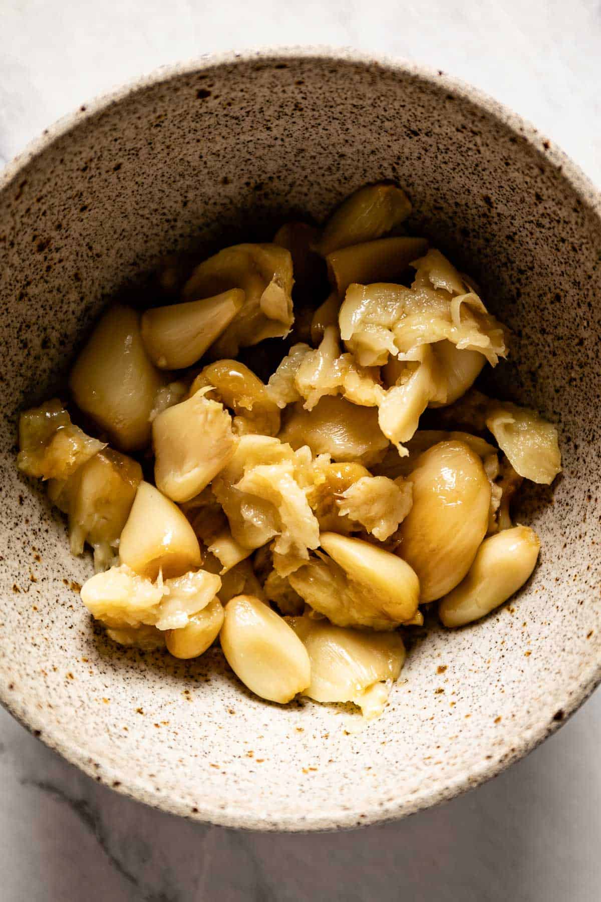 A bowl of peeled, roasted garlic from the top view. 