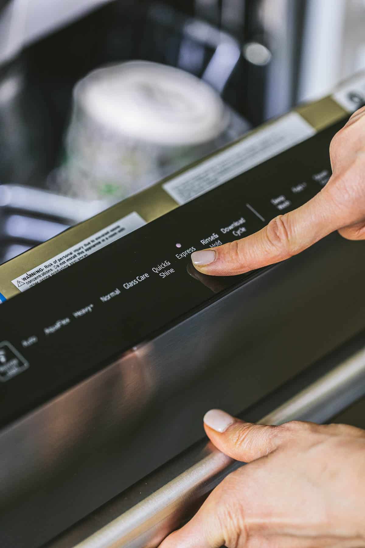 person programming a dishwasher.