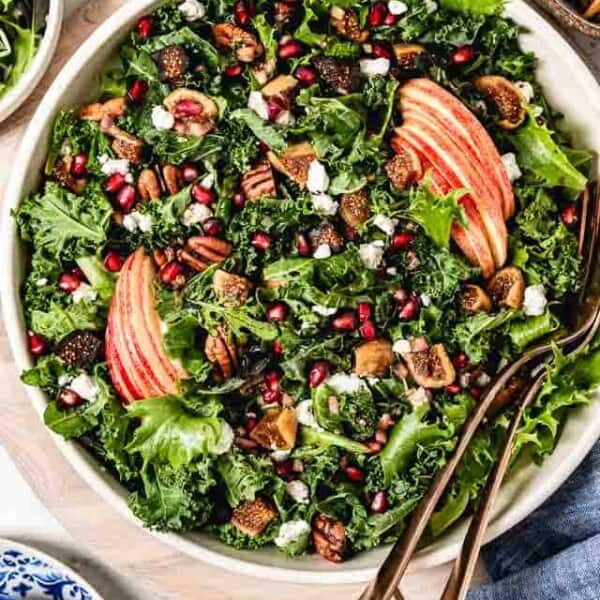 Fall salad garnished with apples and pomegranate arils in a bowl.