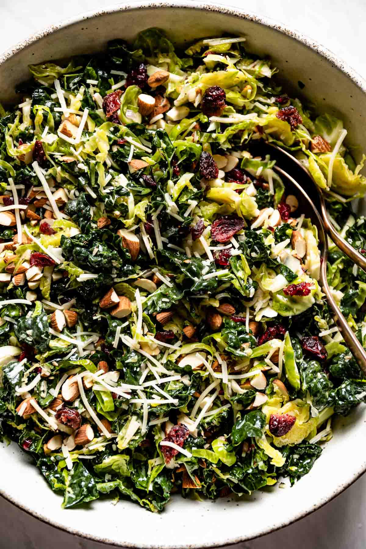 Kale Brussels Sprout Salad in a bowl with spoons on the side.