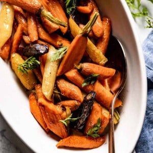 Maple glazed carrots in a plate with a spoon on the side.