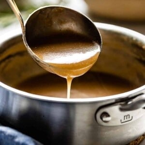 Gravy in a ladle over a pot from the side view.