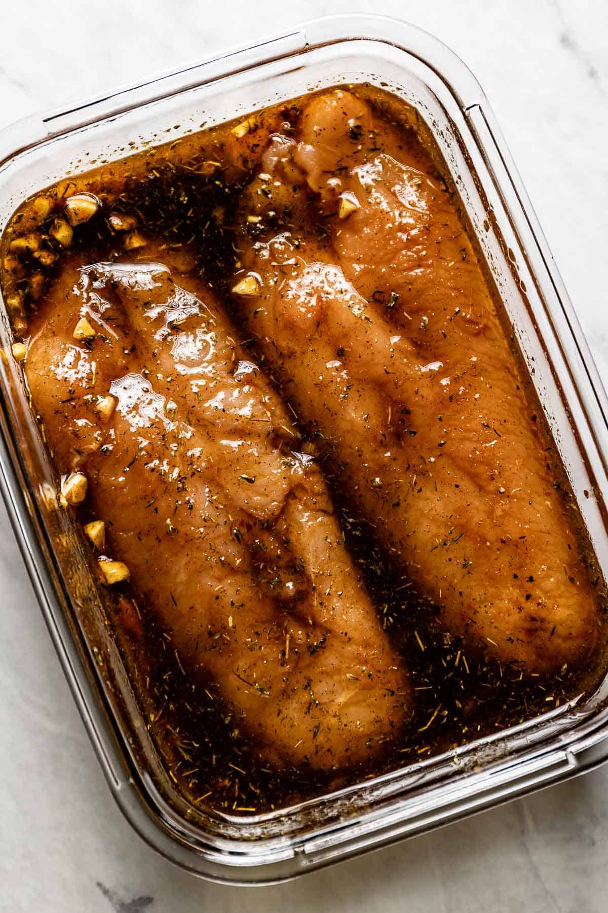 Turkey meat marinating in a bowl with spices and soy sauce from the top view.