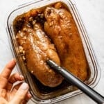 A person marinating turkey in a bowl from the top view.