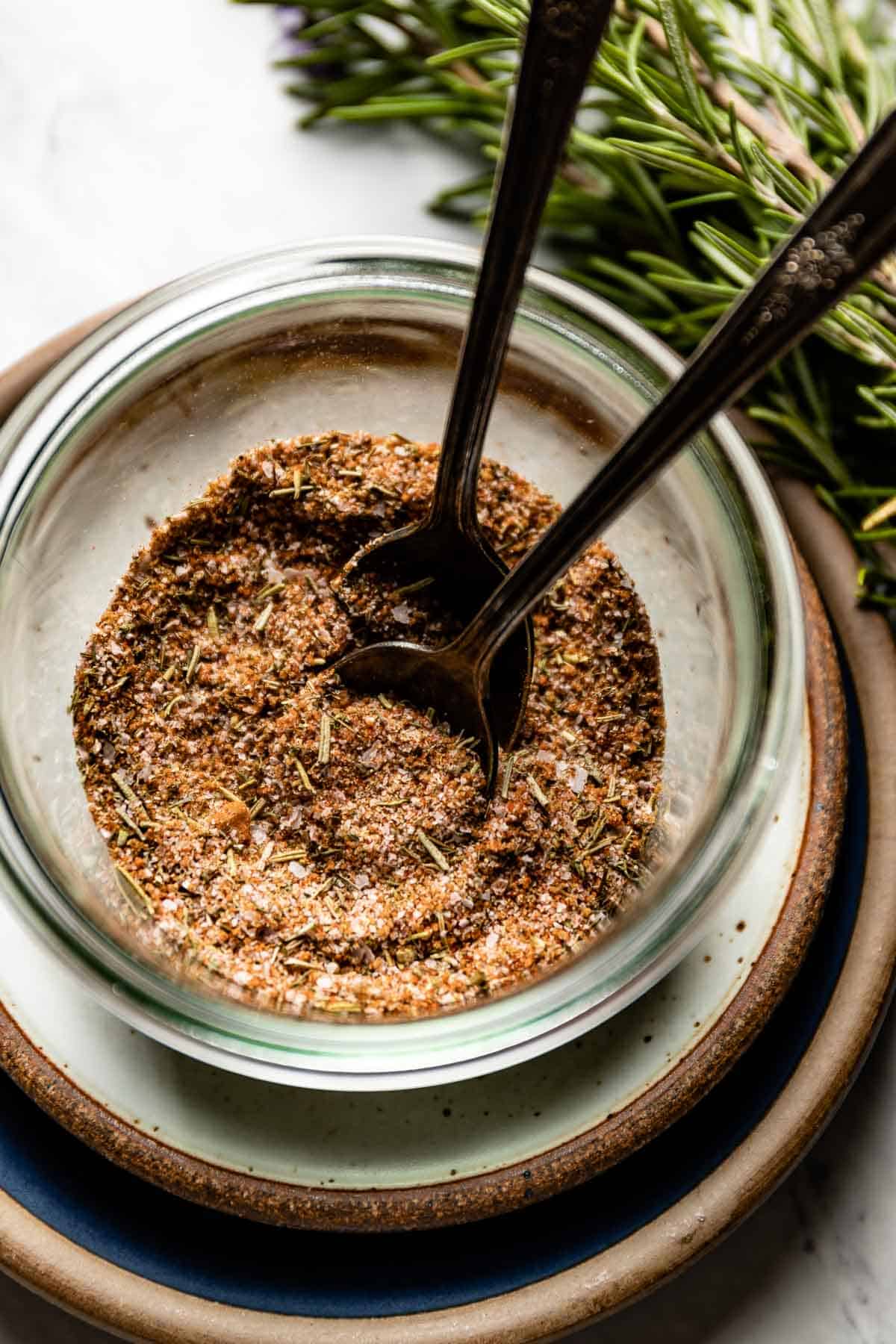 A blend of herbs and spices in a bowl with spoons from the top view.