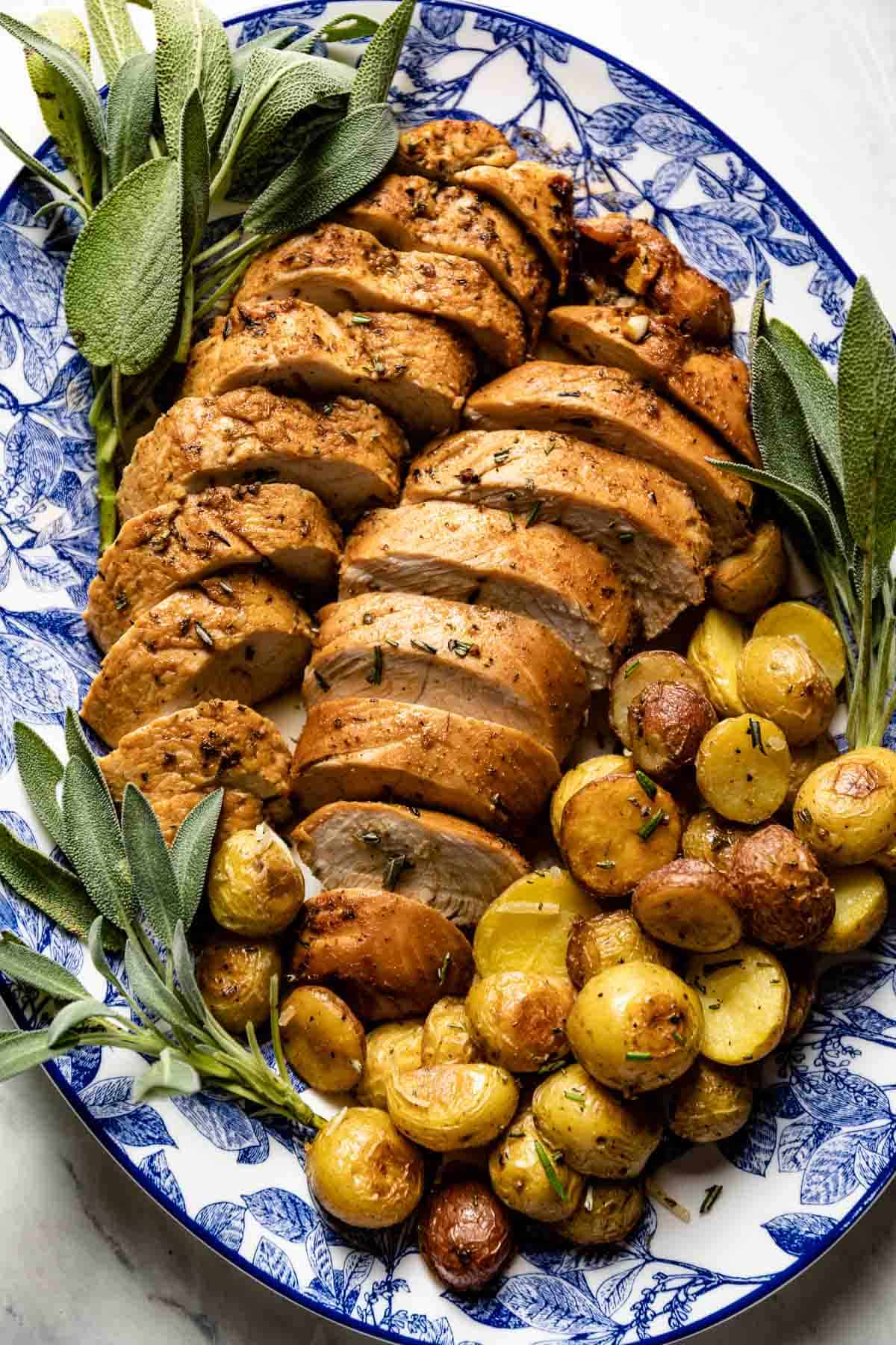 Baked turkey breast tenderloin on a plate with potatoes from the top view.