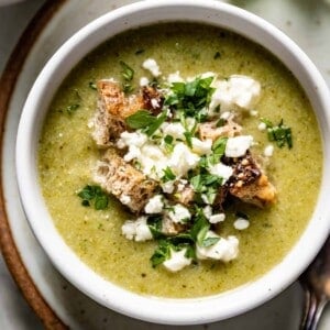 A bowl of Feta Broccoli Soup garnished with parsley and croutons from the top view.