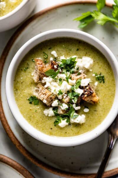 A bowl of Feta Broccoli Soup garnished with parsley and croutons from the top view.