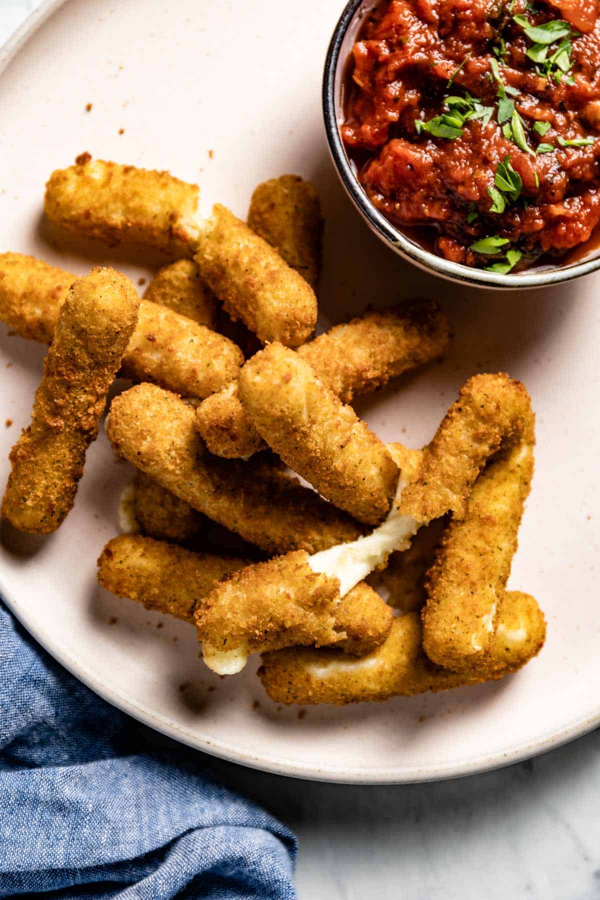 Crispy cheese sticks served on a plate with tomato sauce from the top view.