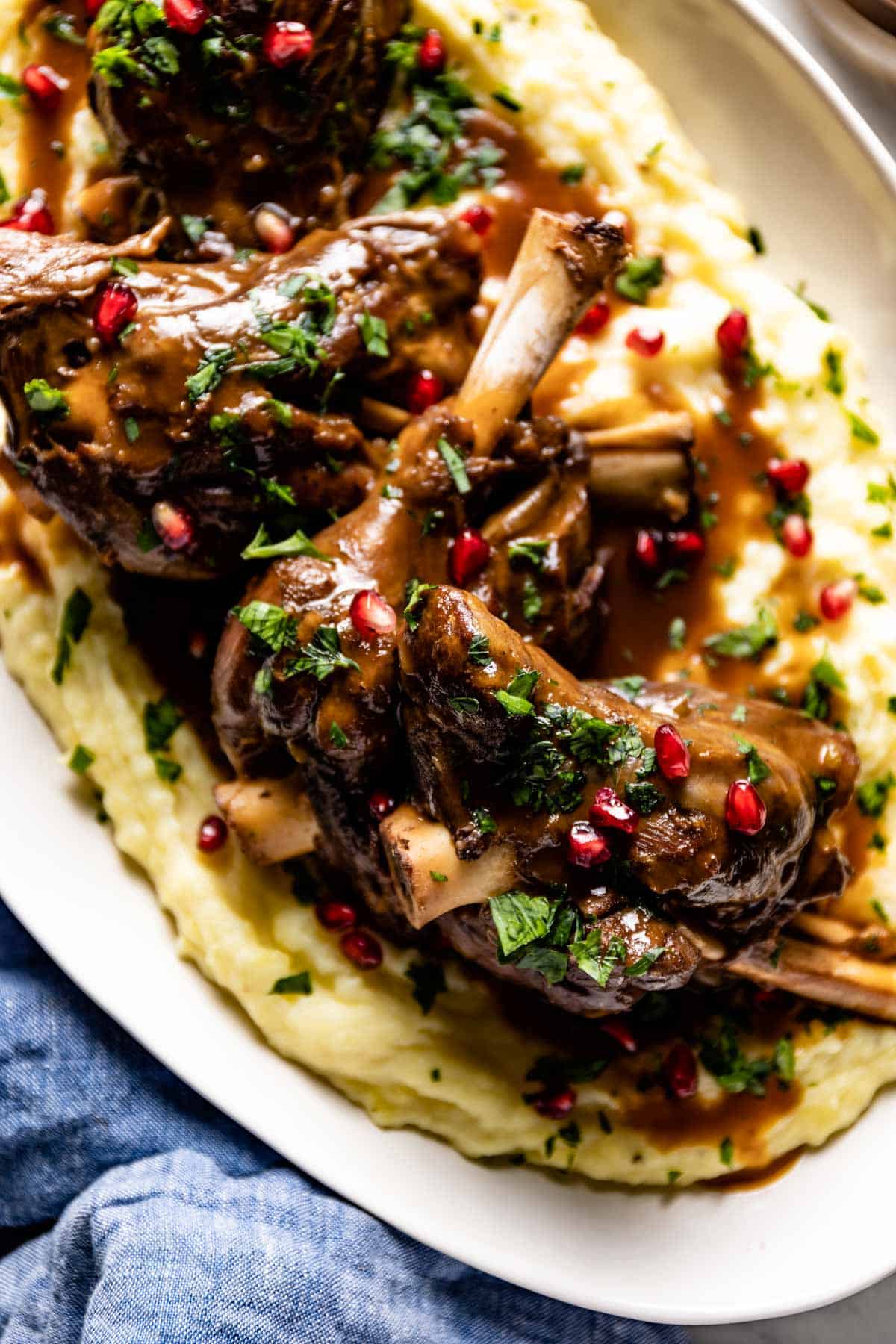 A close up view of cooked lamb garnished with pomegranate seeds.
