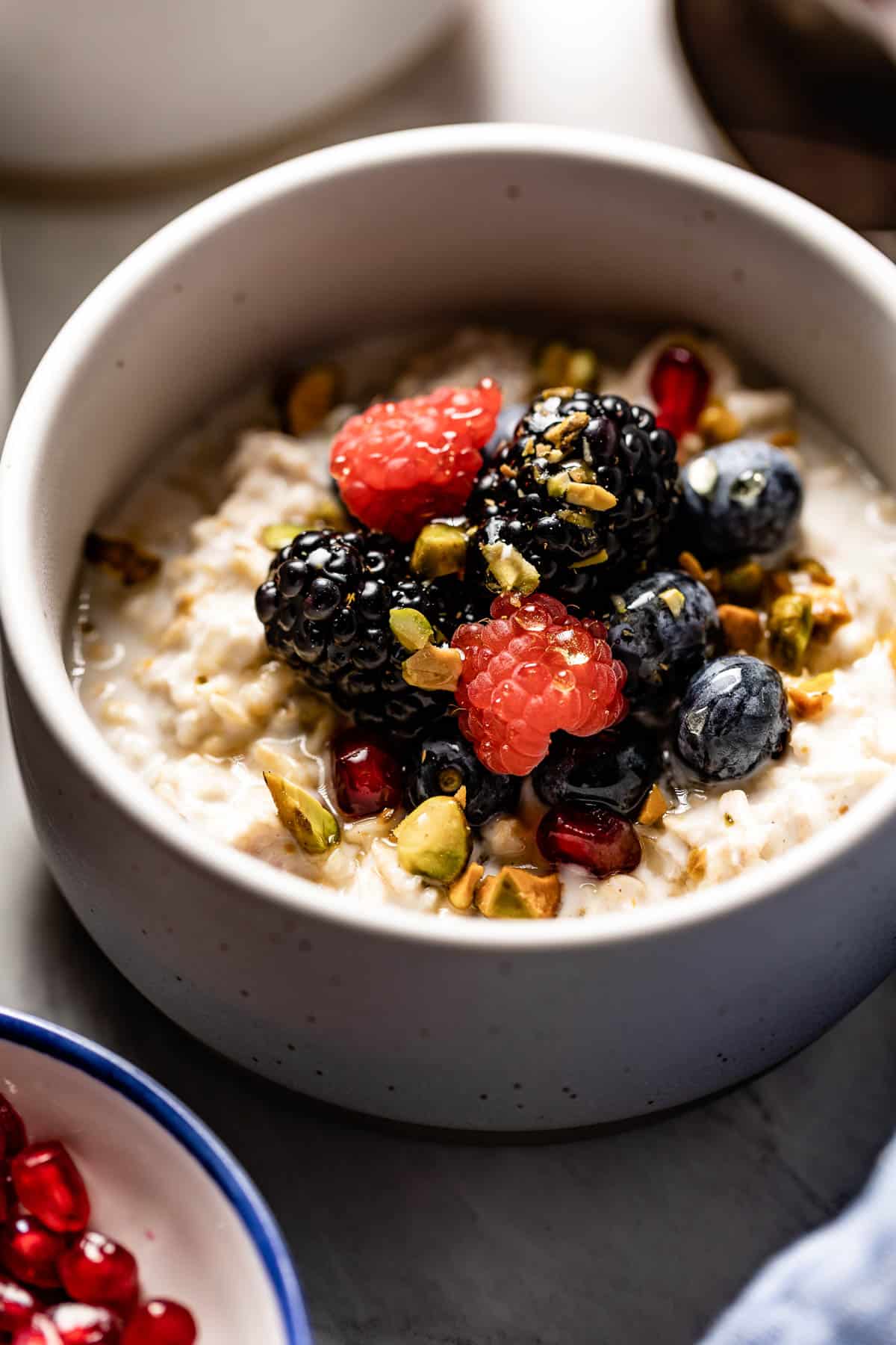 A bowl of oats topped with fruit and nuts from the side view.