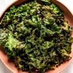 A bowl of baked kale leaves shown from the top view.