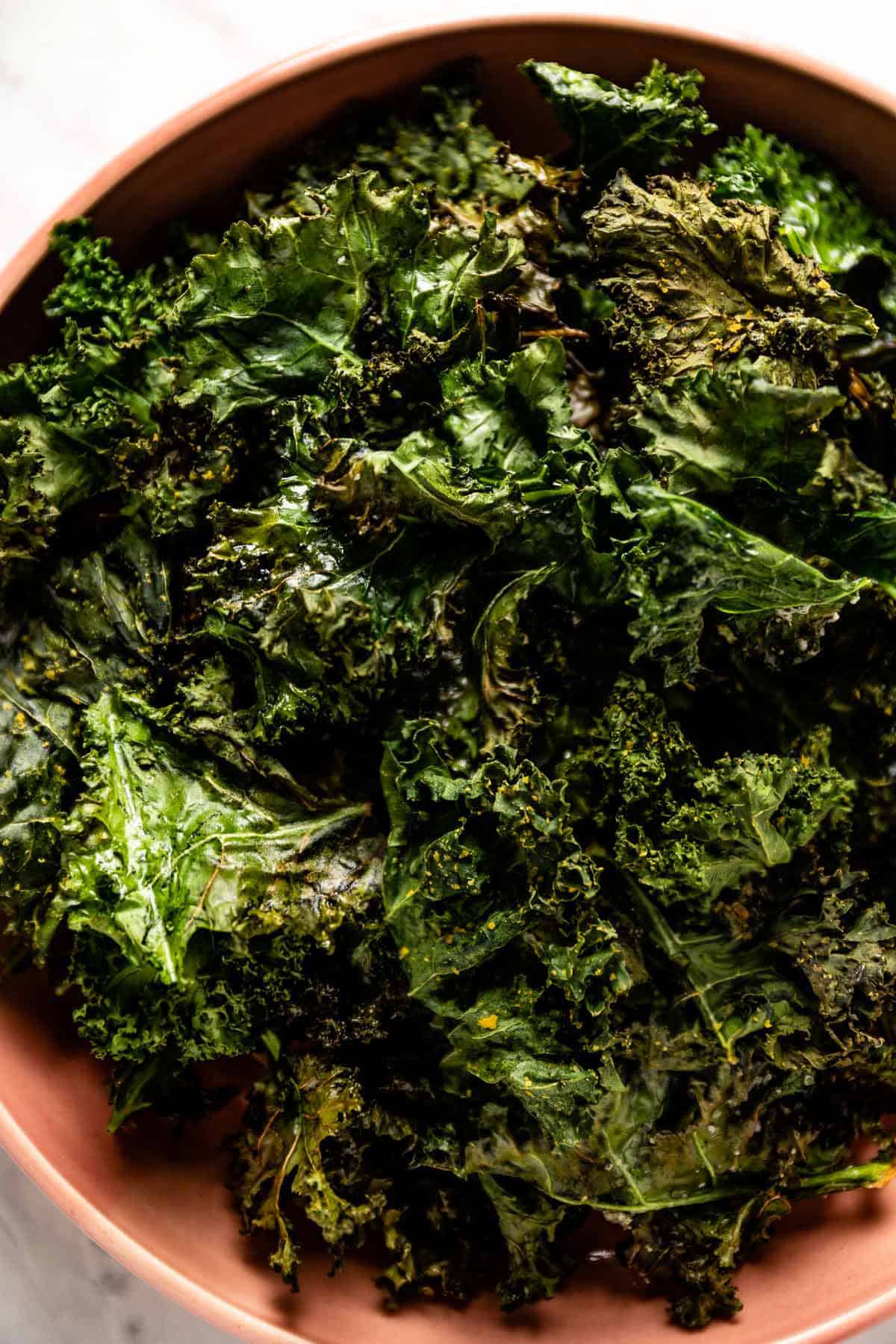 Crispy pieces of air-fried kale in a bowl from the top view. 