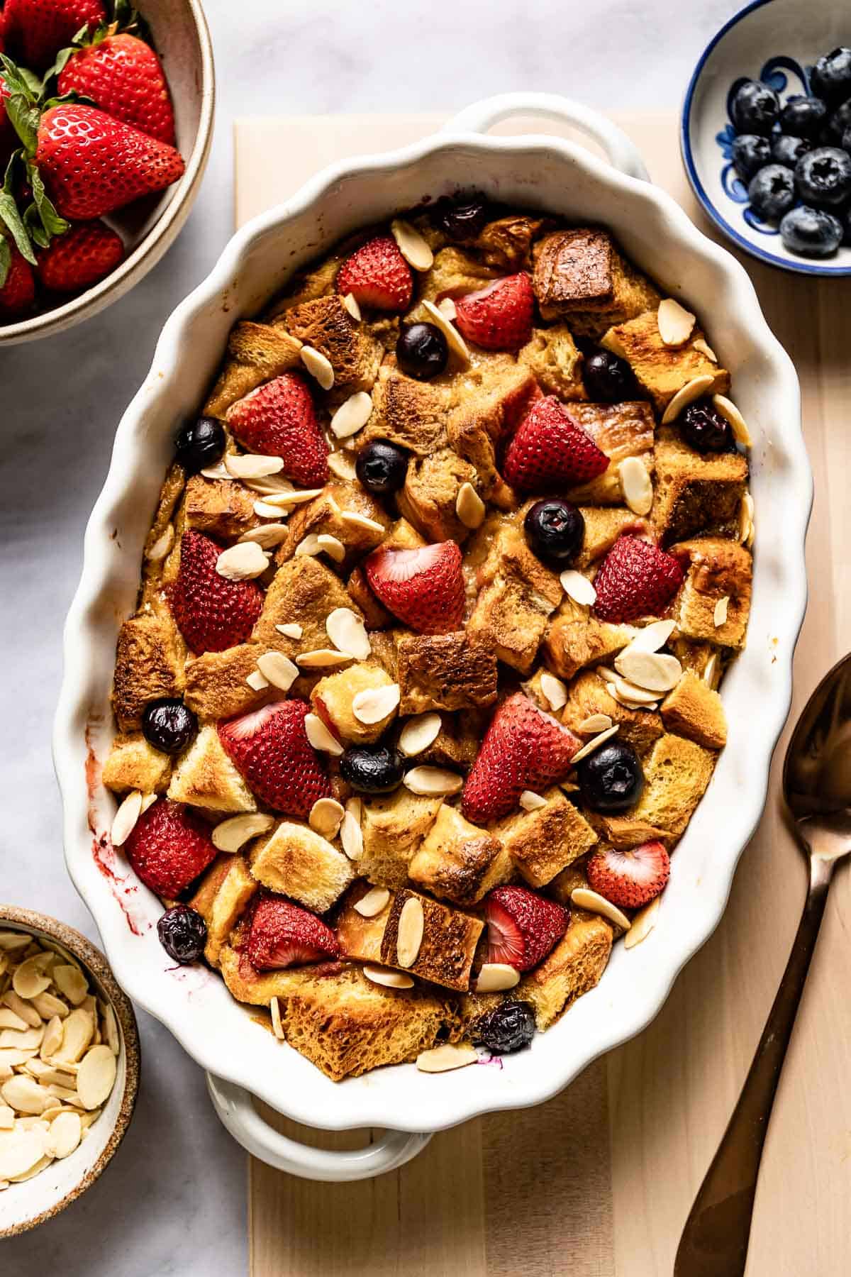 A breakfast casserole with brioche topped with berries and almonds. 